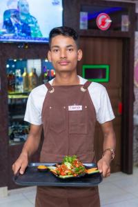 a man holding a tray of food on a plate at Hotel Royal Inn, Nuwakot in Trisūli Bāzār
