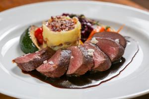 a plate of food with meat and fruit on it at Apartment Chalet Kladska in Mariánské Lázně