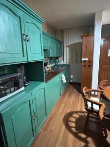 a kitchen with green cabinets and a table with a microwave at Acogedor y céntrico Departamento in León