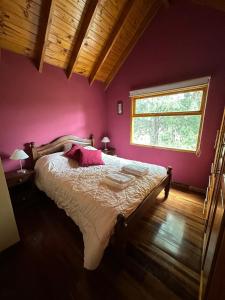 a bedroom with a bed with pink walls and a window at Aromas de Montaña VIP in Junín de los Andes