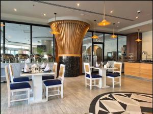 a restaurant with white tables and chairs and a kitchen at Rona Al Khobar Hotel in Al Khobar