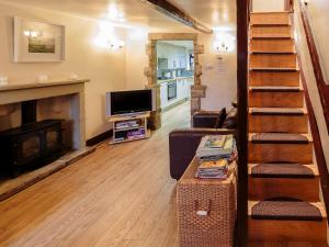 a living room with a fireplace and a television at Millstone Cottage in Bradwell