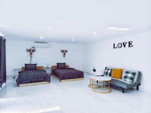 a bedroom with two beds and a couch and a table at Joy Pool House in Kuta