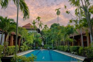 a swimming pool in front of a resort with palm trees at Green Morodoc Garden Hotel in Siem Reap