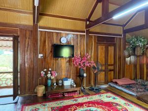 a living room with wood paneled walls and a tv at The Bare Nest Retreat - Xóm Đung Homestay in Hòa Bình