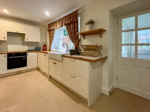 a kitchen with white cabinets and a sink and a window at Grieves Cottage - Uk50908 in Cupar +17 photos