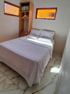 a bedroom with a white bed with a marble floor at Chalé das águas in Cunha