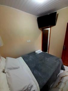 a bedroom with a bed with a tv on the wall at Chalé das águas in Cunha +10 photos