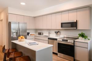 a kitchen with white cabinets and stainless steel appliances at Sense28 Edgewater, an AvantStay Hotel in Miami