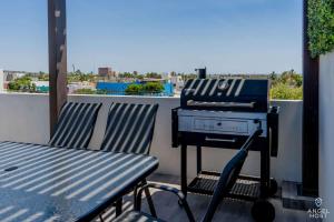 a grill sitting on a balcony with two chairs at Pool BBQ & a Short Walk to the Malecon in La Paz