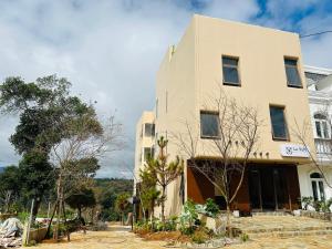a building on a street with trees in front of it at Le VyN Mang Den in Kon Plong