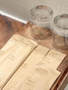a wooden table with two glasses and paper napkins at La Grotta Hotel - Phu Quoc Emerald Bay in Phú Quốc