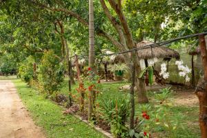 a garden with a fence and some flowers and trees at Sayon River Cottage in Wellawaya