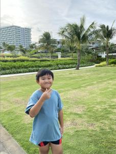 a young boy is standing in a park at Alma Resort - Căn hộ in Cam Lâm