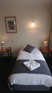 a bedroom with a bed with a towel on it at Mt Lyell Motor Inn - By Orangepete in Queenstown