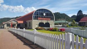 a building with a white fence in front of it at Mt Lyell Motor Inn - By Orangepete in Queenstown