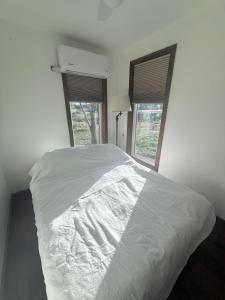 a white bed in a bedroom with two windows at Private Ranch Retreat in Banning