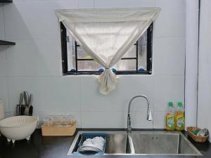 a kitchen sink with a window with a curtain at Cốm Homestay in Hue +26 photos