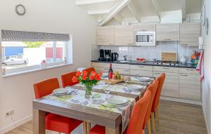 a dining room table with orange chairs and a kitchen at Maasvilla - Amfibie - 31 in Ohé en Laak
