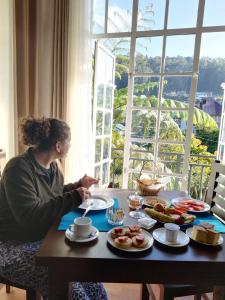 a woman sitting at a table with plates of food at Star Gate Hostel in Nuwara Eliya
