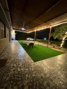 a patio with a table and a green lawn at night at Aura Villa in Delmāra