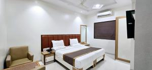 a bedroom with a bed and a chair and a television at Hotel Paradise Ahilyanagar in Ahmadnagar