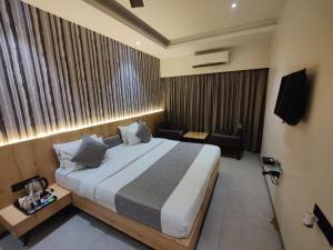 a hotel room with a large bed and a couch at Hotel Paradise Ahilyanagar in Ahmadnagar