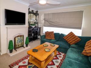 a living room with a green couch and a table at 5 Overstone Drive in Wisbech