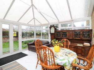 a conservatory with a table and chairs and a couch at 5 Overstone Drive in Wisbech