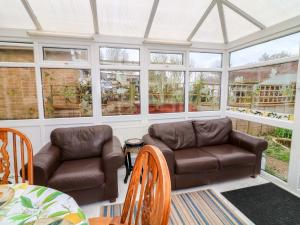 a conservatory with two leather chairs and a table at 5 Overstone Drive in Wisbech