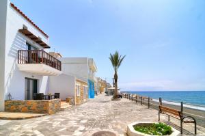 a walkway next to the ocean with a palm tree at Myrtos Mare Suites in Myrtos