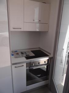 a small white kitchen with a stove top oven at Les pieds dans la mer Best place in Villefranche-sur-Mer