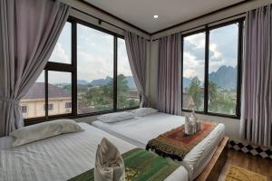 two beds in a room with large windows at SD View Hotel in Vang Vieng