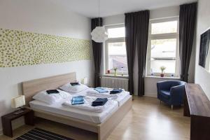 a bedroom with a bed and a chair and windows at Stilvolle Altbauwohnung in zentraler Lage in Kiel