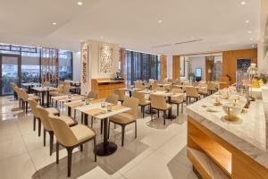 a dining room with tables and chairs and windows at Alino Hotel in Manila