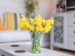 a vase filled with yellow flowers on a table at Wisteria Cottage in Heathfield +17 photos