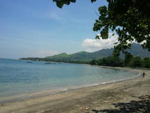 a beach with a person walking on the water at Biorock Homestay & Dive Center Pemuteran in Pemuteran