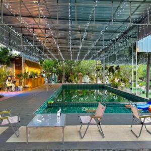 a pool with two chairs and a table in a building at Ban Mali Cafe & Riverside Stay in Ban Chang