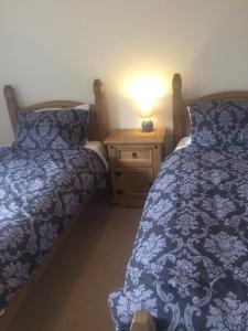 1 dormitorio con 2 camas y mesita de noche con lámpara en An Teallach en Oban