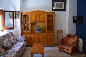 sala de estar con armario de madera y TV. en Apartaments Bizantí, en Sant Martí d’Empúries