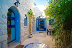 un patio con puertas azules, mesa y sillas en Artist Quarter Guesthouse B&B en Safed
