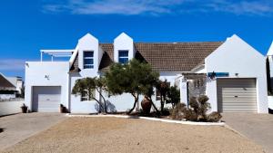 a white house with two garage doors and trees at Anchorage in Stompneusbaai