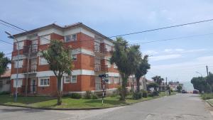 een rood bakstenen gebouw met palmbomen voor een straat bij Departamento del Mar in Mar del Plata