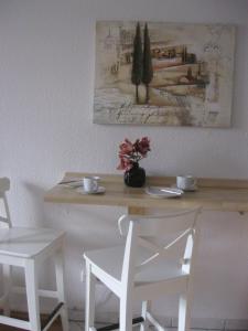 einem Holztisch mit zwei weißen Stühlen und einem Tisch mit Blumen darauf in der Unterkunft Zum Augustiner in Erfurt