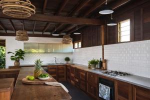 a kitchen with wooden cabinets and a table with fruits on it at KAZ DIBWA Beach House in Glacis