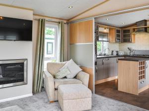 a living room with a chair and a kitchen at Lavender Lodge in Patrington