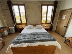 a large bed in a room with two windows at Chambres d’hôtes Le relais de Mantelot in Châtillon-sur-Loire