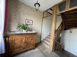 a room with a staircase and a wooden cabinet with a potted plant at Chambres d’hôtes Le relais de Mantelot in Châtillon-sur-Loire