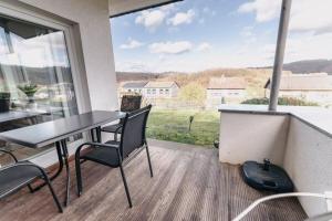a patio with a table and chairs on a balcony at Ferienhaus Waldzeit in Heimbach +34 photos