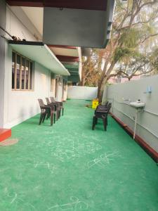 a building with a green floor with chairs on it at Sumathinandanakuteer in Pithāpuram